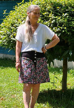 Femme portant une Jupe Améthyste fleurie avec un haut blanc, dans un jardin, patron de couture pdf à télécharger disponible.
