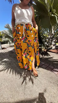 Femme portant la Jupe Astéria - T36 à 50 avec motif floral lumineux, patron de couture pdf à télécharger, sous un ciel ensoleillé.