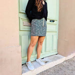 Jupe Georgia - T34 à 48 avec motif patchwork, patron de couture PDF à télécharger, modèle tendance devant une porte verte.