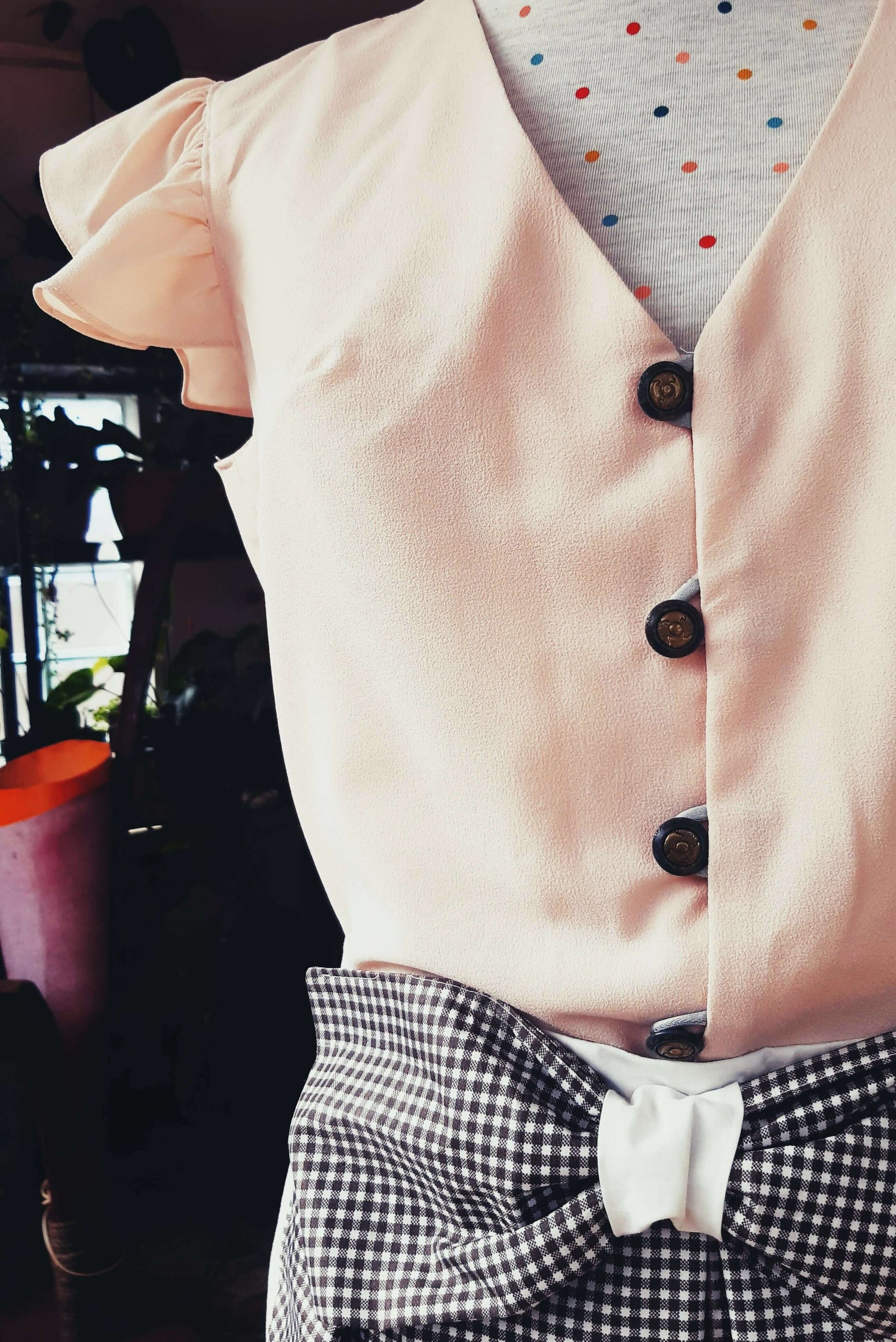 Robe vintage avec boutons et ceinture à nœud, style rétro années 60, focus sur le haut du buste.