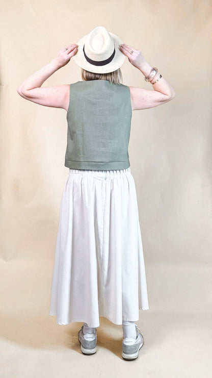 Femme portant une Jupe Lola blanche, vue de dos, complétée par un top vert et un chapeau, patron de couture pdf à télécharger inclus.