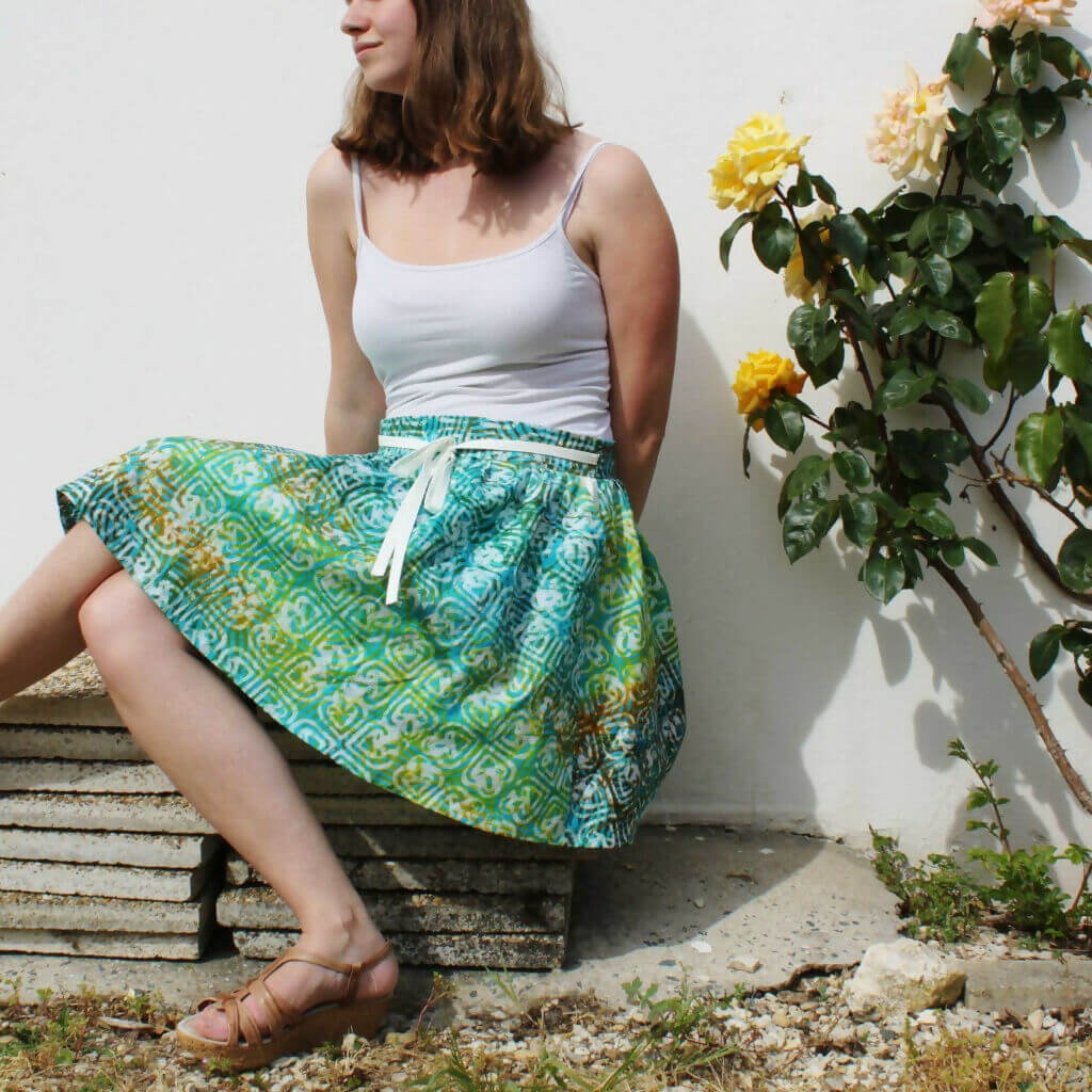 Femme portant la Jupe Málaga - 32 au 56, patron de couture pdf à télécharger, avec un design paperbag et poches italiennes.