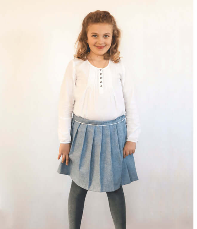 Enfant portant une Jupe Oxford, patron de couture pdf à télécharger, jupe plissée au-dessus du genou avec ceinture élastique.