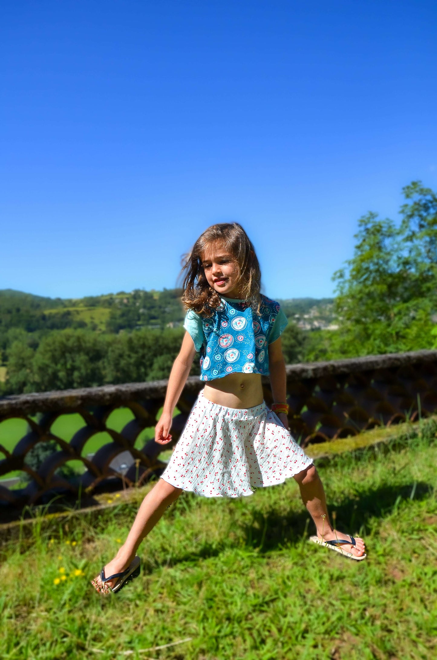 Fille joyeuse portant un jupe-short dans la nature, idéale pour jeux d'été et mouvement.