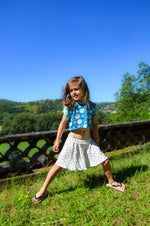 Fille joyeuse portant un jupe-short dans la nature, idéale pour jeux d'été et mouvement.