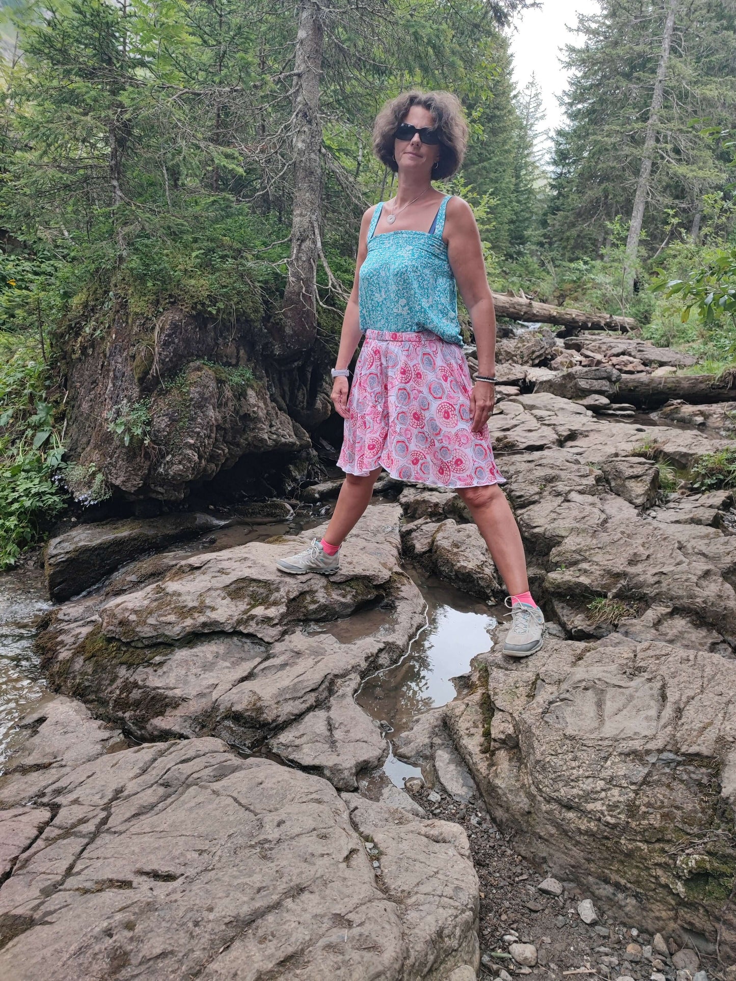 Femme en jupe-short LILAS, posant sur des rochers, parfait pour l'été, alliant confort et élégance.