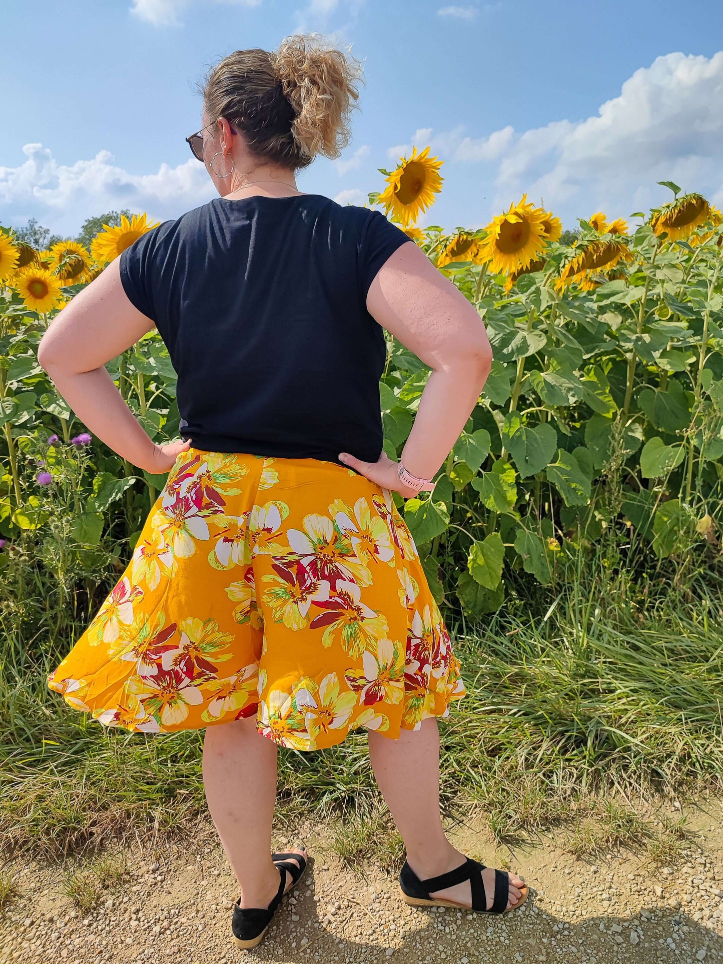 Femme portant un jupe-short LILAS dans un champ de tournesols, parfaite pour l'été et les activités en plein air.