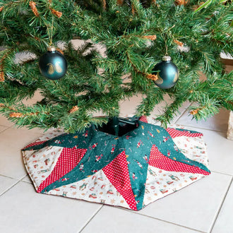 Jupe de sapin de Noël étoilée en tissu, embellissant le pied d'un arbre, avec motifs festifs et ornements.