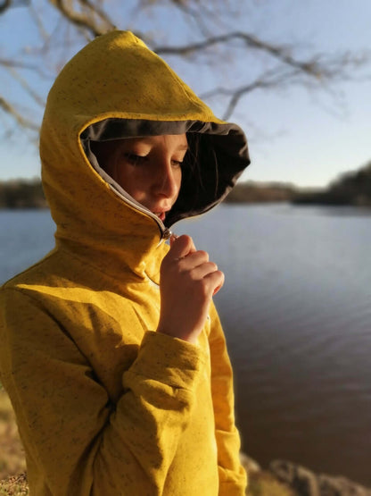 LE SWEAT ZIP ZAG 6- 16 ans porté près d'un lac avec une capuche unique et zip diagonal, idéal pour les jeunes.