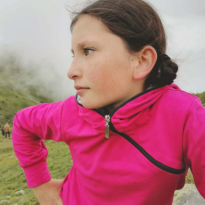 LE SWEAT ZIP ZAG 6- 16 ans porté par une enfant en extérieur, style original avec zip diagonal et capuche.