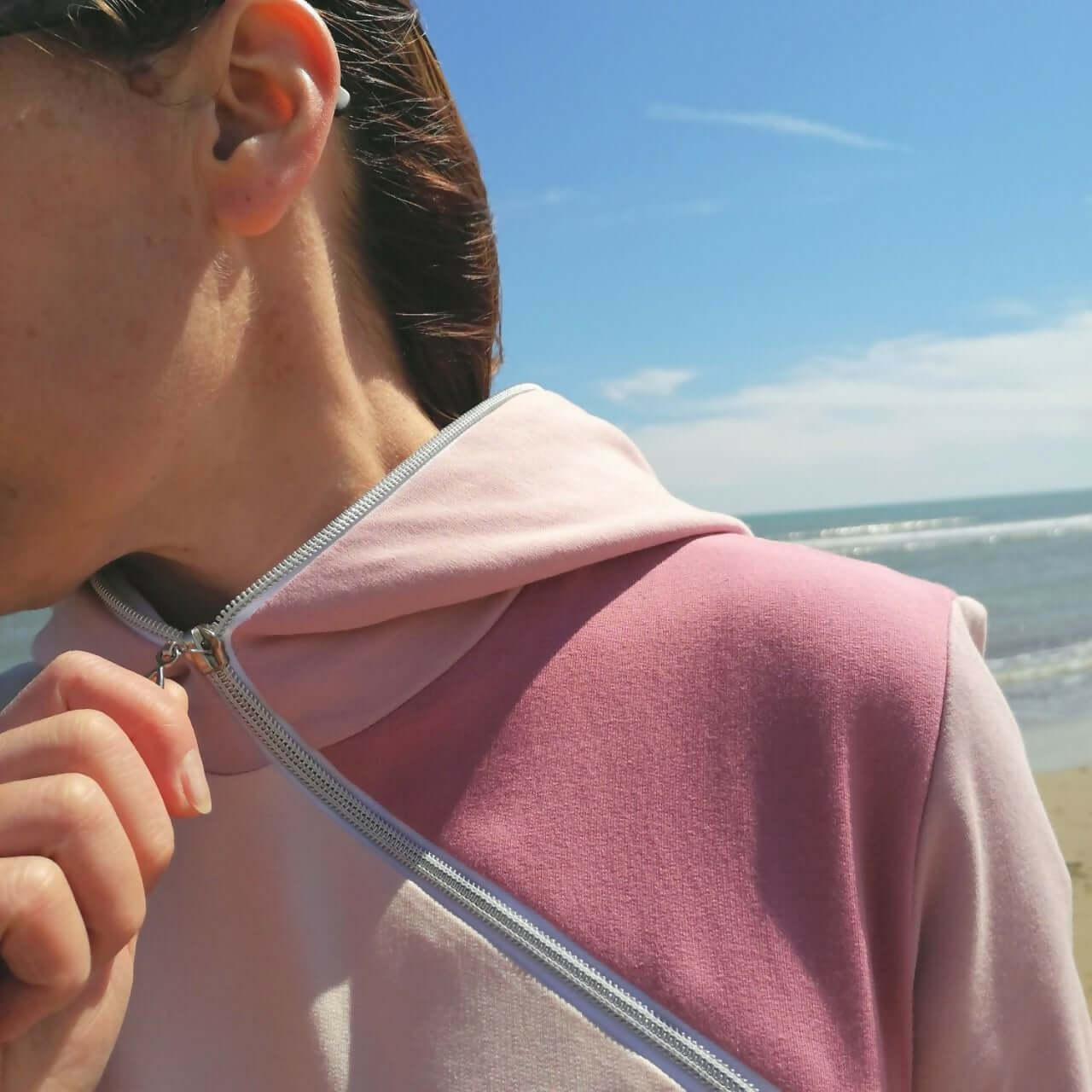 LE SWEAT ZIP ZAG du XS au XXL - Zoom sur le zip diagonal et la capuche sur fond de plage.