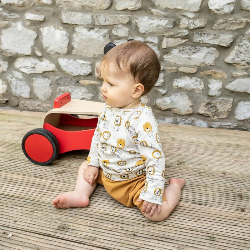 Bébé portant LITCHI : t-shirt, sweat et robe en un patron, sur une terrasse, avec patron de couture pdf à télécharger à l'arrière-plan.
