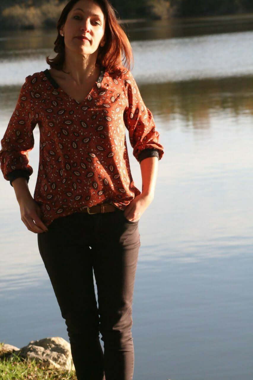 La Blouse CYCLADINE du 34 au 52 portée par une femme près d'un plan d'eau, style sport-chic et élégant.