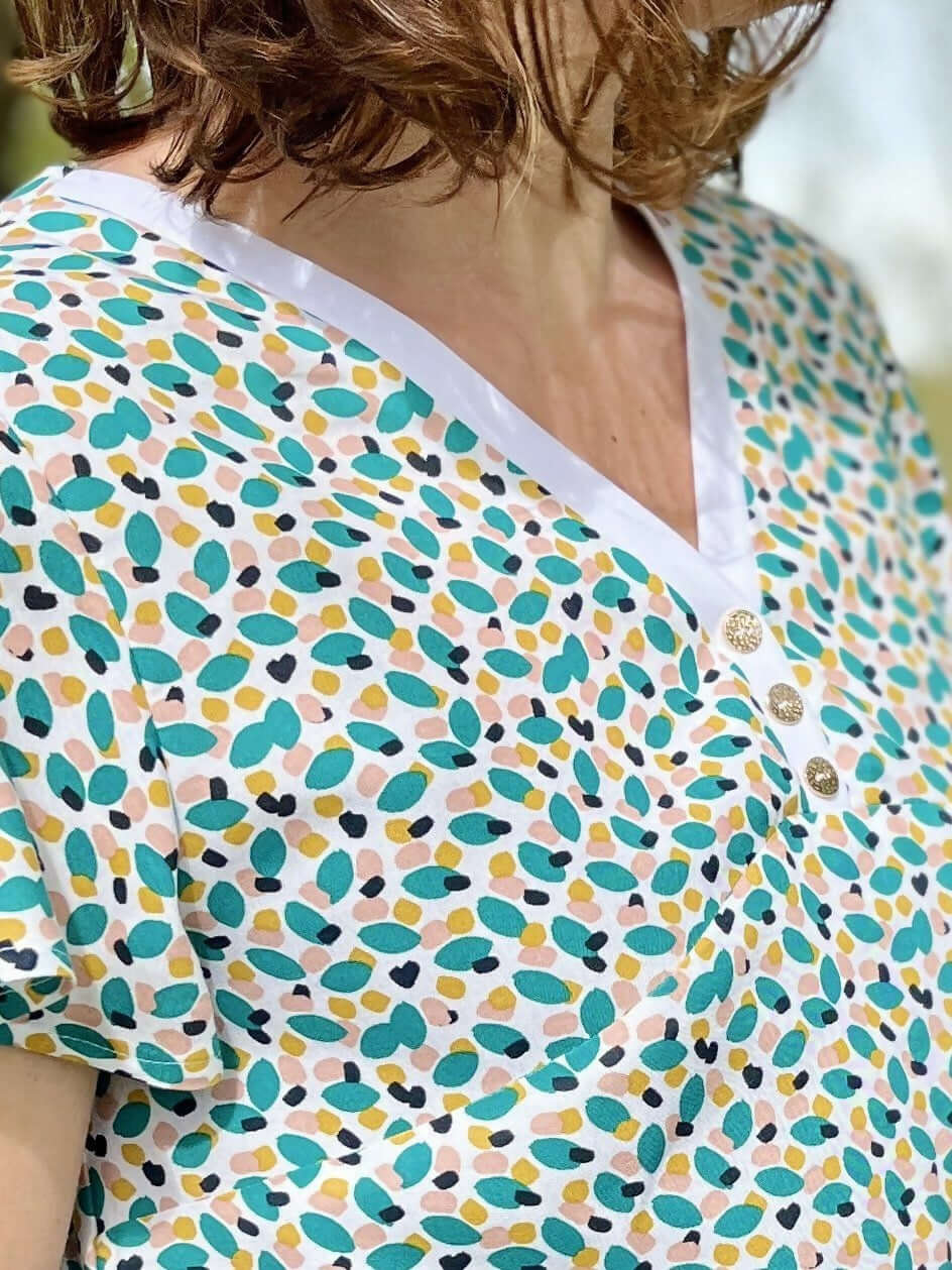 La blouse COLYNE du 34 au 48, avec encolure V et boutons, idéale pour un look sport chic.