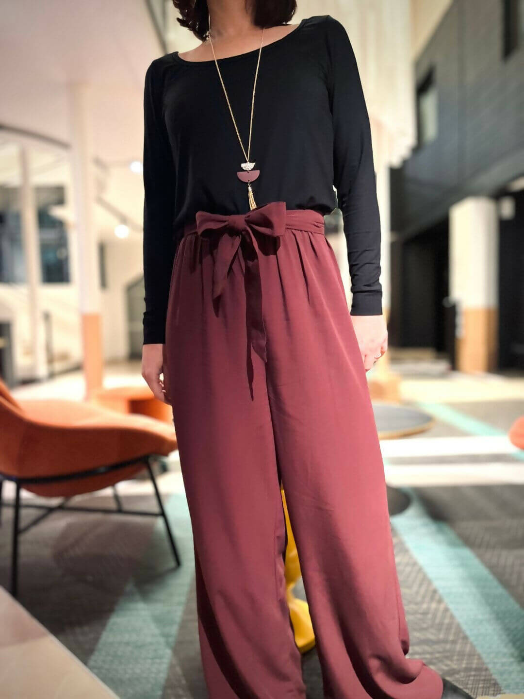 Femme portant la combi Blend Du 32 au 52, patron de couture pdf à télécharger, avec haut noir en jersey et bas fluide bordeaux.