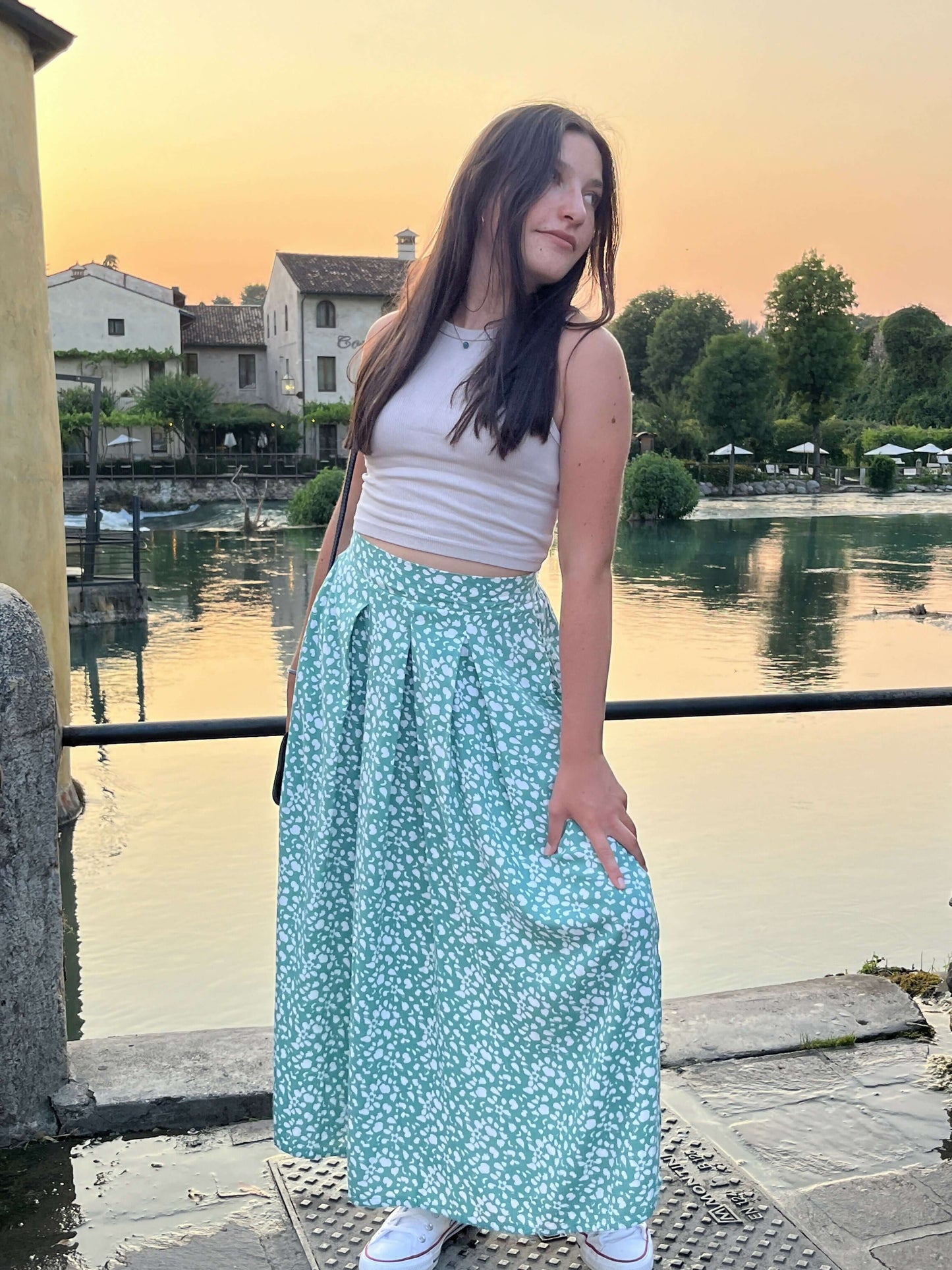 Jeune femme portant La jupe EOLYA du 32 au 52, patron de couture pdf à télécharger, avec vue sur la rivière au coucher du soleil.