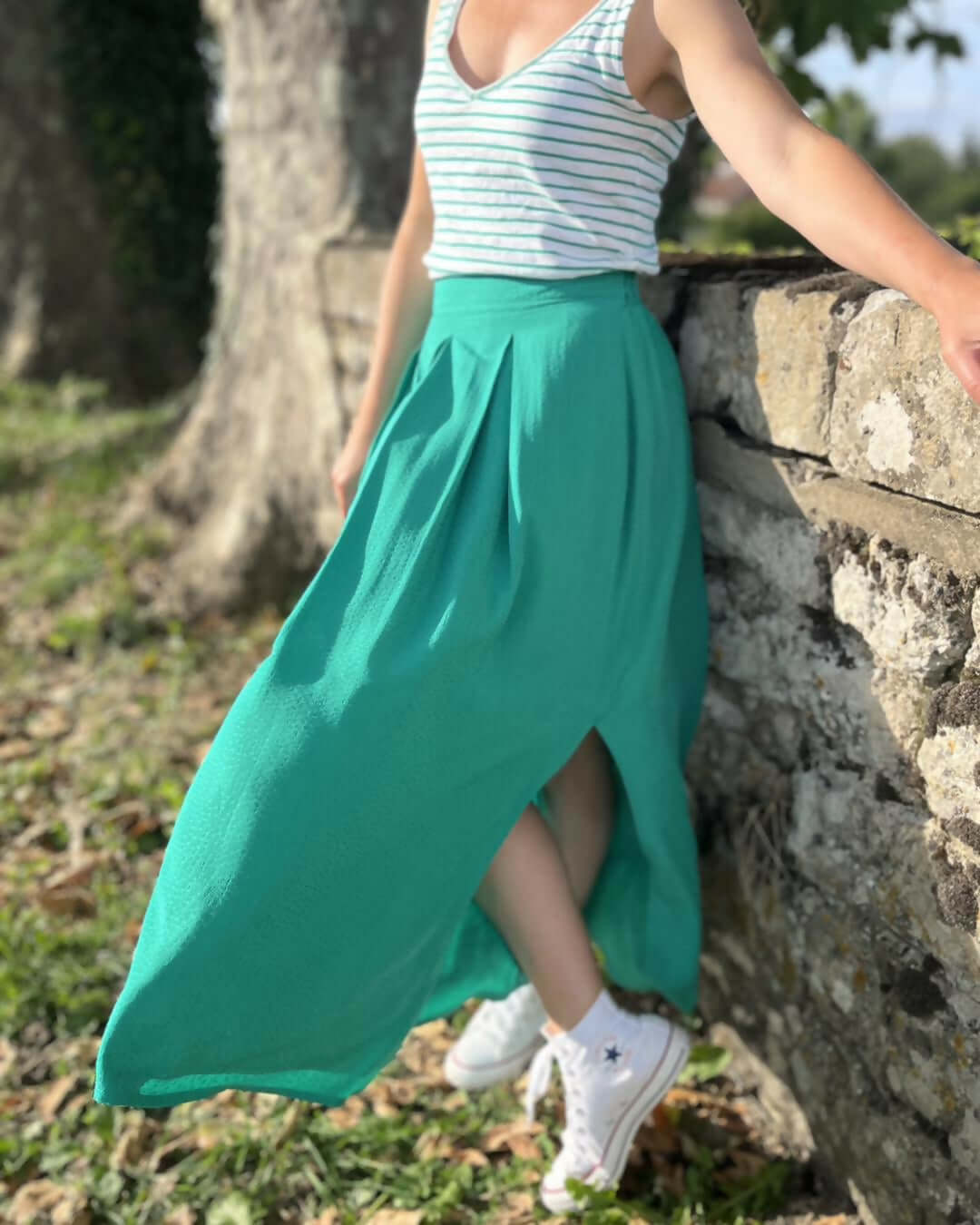 La jupe EOLYA du 32 au 52, patron de couture pdf à télécharger, montrée en vert avec une fente latérale et un design élégant.