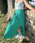 La jupe EOLYA du 32 au 52, patron de couture pdf à télécharger, montrée en vert avec une fente latérale et un design élégant.