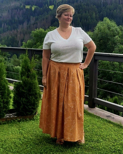 Femme portant la jupe EOLYA du 32 au 52, patron de couture pdf à télécharger, en plein air sur une terrasse verdoyante.