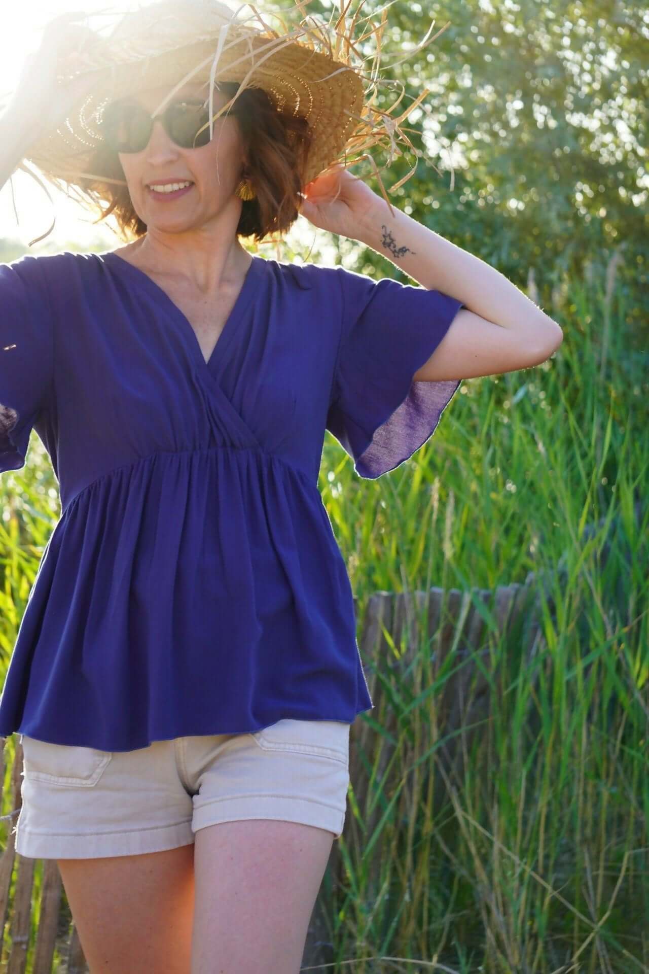 Femme portant la robe (ou blouse) Sorelle du 32 au 52, style élégant, en tissu léger, avec chapeau de paille.