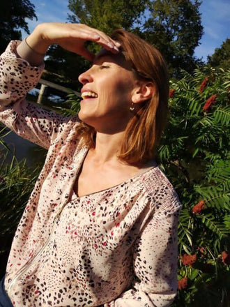 Femme souriante portant La veste BLOOMY du 34 au 46 dans un cadre nature, ajoutant style et féminité.