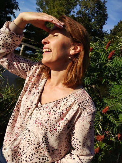 Femme souriante portant La veste BLOOMY du 34 au 46 dans un cadre nature, ajoutant style et féminité.