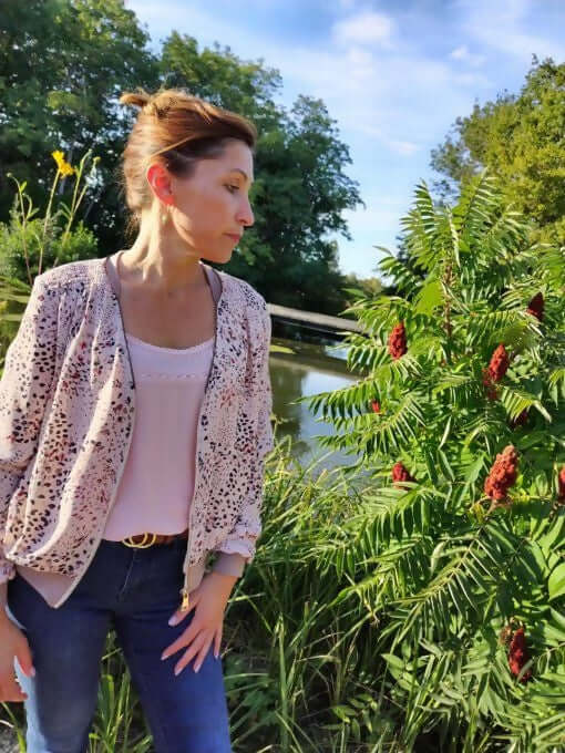 Femme portant La veste BLOOMY du 34 au 46 au bord d'un étang, style sportswear, floral, avec un top et un jean.