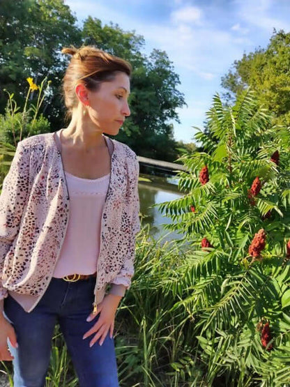 Femme portant La veste BLOOMY du 34 au 46 au bord d'un étang, style sportswear, floral, avec un top et un jean.