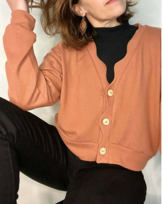 Le Gilet Vinka du 32 au 52 en couleur orangée, au style ample, avec boutons et patte ondulée originale.