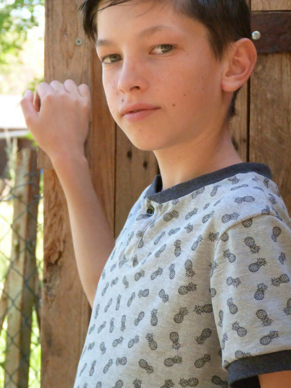 Le Polo ENJOY le Polo du 6 au 16 ans porté par un jeune garçon en extérieur, avec motifs ananas.