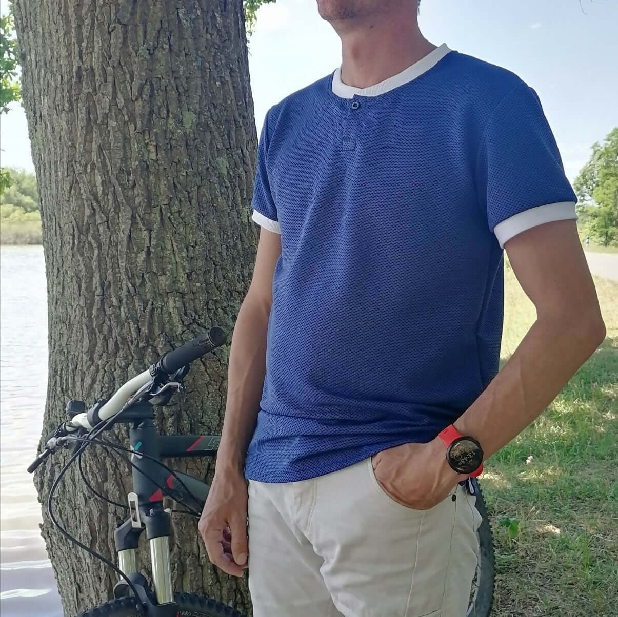 Le Polo Enjoy Homme du 38 au 50 porté en extérieur près d'un vélo, idéal pour un look décontracté.