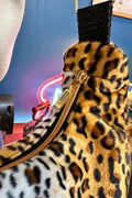 Sac à main en fausse fourrure léopard avec fermeture éclair et bandoulière, style moderne et audacieux.