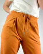 Le pantalon Sprint du 32 au 52, patron de couture pdf à télécharger, en tissu orange avec taille haute et coupe confortable.