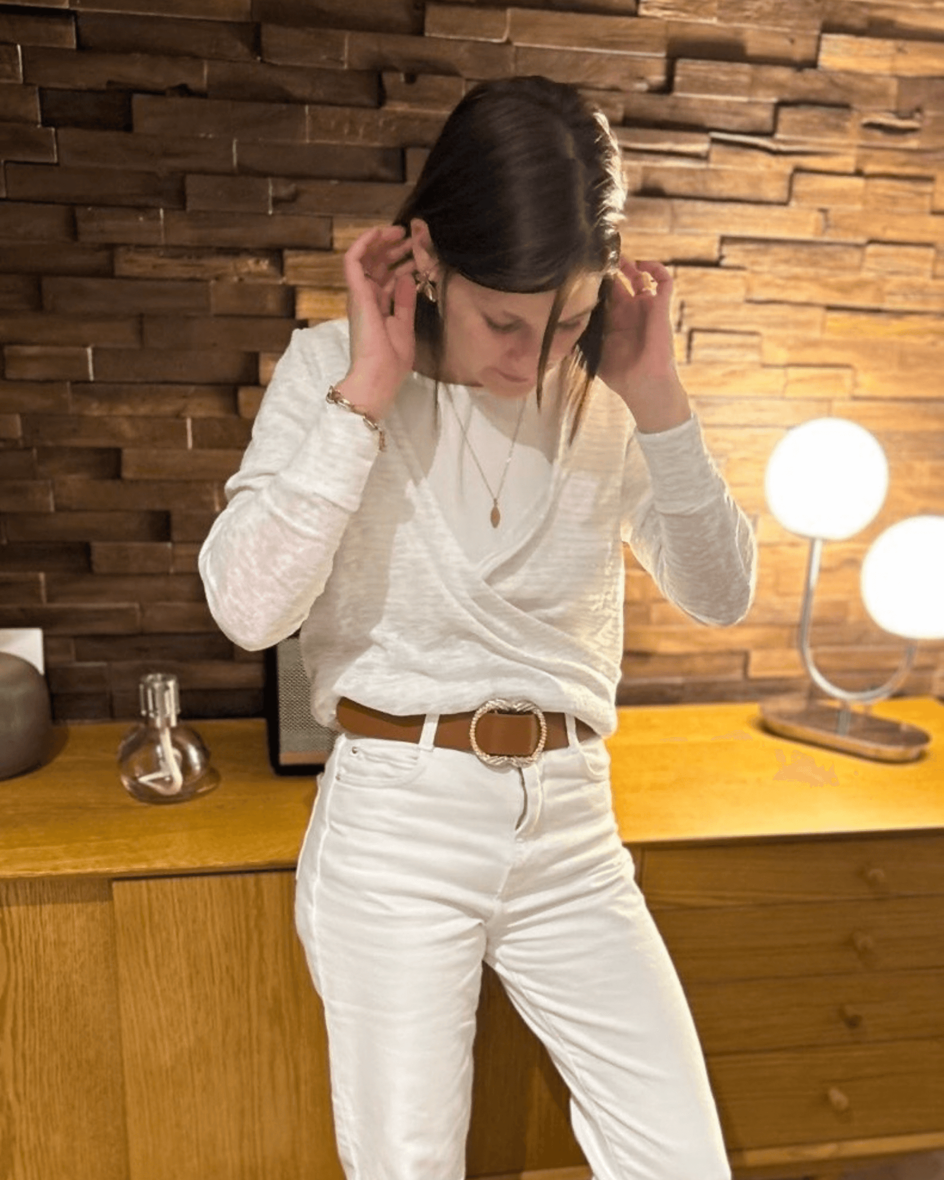 Femme portant le pull Axia du 32 au 52, patron de couture PDF à télécharger, en version cache-cœur réversible sur fond de décoration en bois.