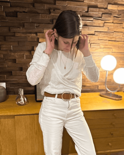 Femme portant le pull Axia du 32 au 52, patron de couture PDF à télécharger, en version cache-cœur réversible sur fond de décoration en bois.