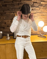 Femme portant le pull Axia du 32 au 52, patron de couture PDF à télécharger, en version cache-cœur réversible sur fond de décoration en bois.