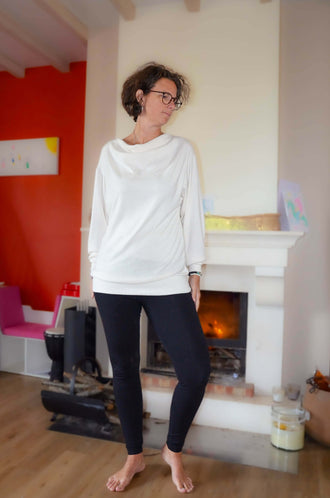 Femme en Legging FIT noir et haut blanc, devant une cheminée, avec le patron de couture pdf à télécharger en option.
