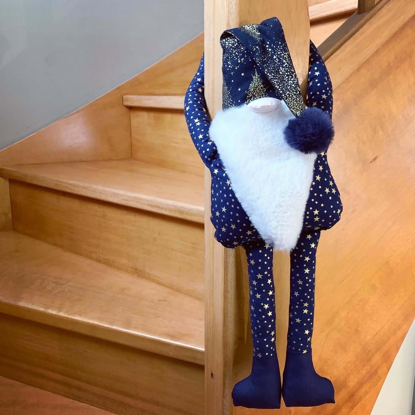 Lutin de Noël à suspendre Séraphin, joyeux décor festif en tissu étoilé, suspendu à un escalier en bois.