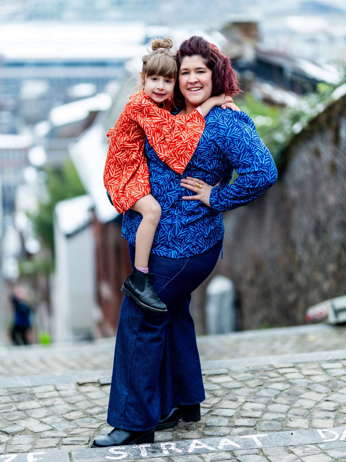Femme et enfant portant des vêtements colorés sur une rue pavée