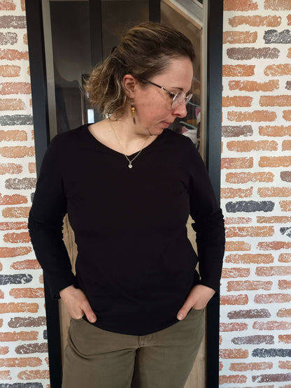 Femme portant un MELLITE - Tshirt / Débardeur noir, manches longues, devant un mur de briques. Patron de couture pdf à télécharger.