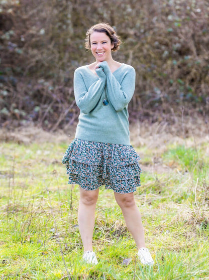 Femme souriante portant MERISE - La jupette à volants dans un champ. Patron de couture pdf à télécharger est disponible.