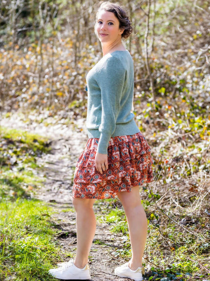 Femme portant MERISE - La jupette à volants, patron de couture pdf à télécharger, parfaite pour tissus fluides, sur chemin de forêt.