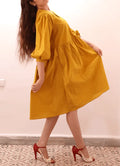 Femme portant la MIMA robe-taille de 30à 58 EU, patron de couture pdf à télécharger. Élégance et confort avec manches bouffantes et poches.