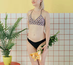 Maillot de bain - XS/L - BREATH avec patron de couture PDF à télécharger, modèle avancé présenté par une femme tenant des fleurs, fond jaune.