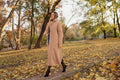 Femme portant un manteau beige en automne, forêt en arrière-plan