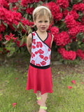 Fille portant la robe Mini-SANDY - Robe cache-coeur pour filles du 2 au 16 Ans, patron de couture pdf à télécharger, devant des fleurs rouges.