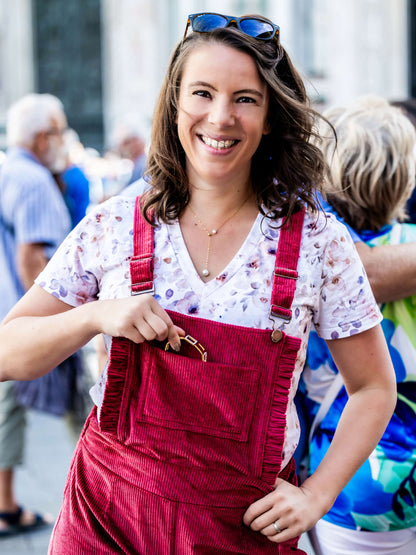 Femme souriante portant une salopette rouge, idéale pour un tuto de couture avec patron PDF.