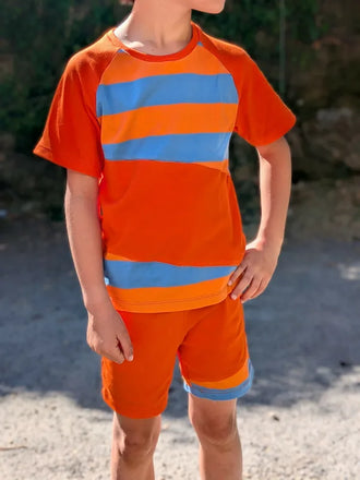 Enfant portant le Patron PDF Pack T-shirt/Short LOULOU et TWIST, rayures bleu et orange, dehors sur chemin de terre