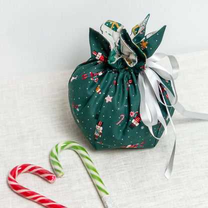 PACK Table de Noël 1, 4 patrons - Sac cadeau en tissu vert avec des motifs de Noël.