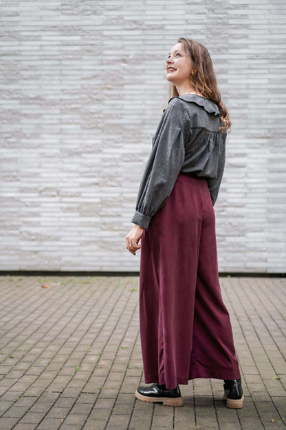 Modèle portant le Pantalon ASTAU - 32 au 56 avec coupe ample, patron de couture pdf à télécharger, en extérieur sur un sol pavé.